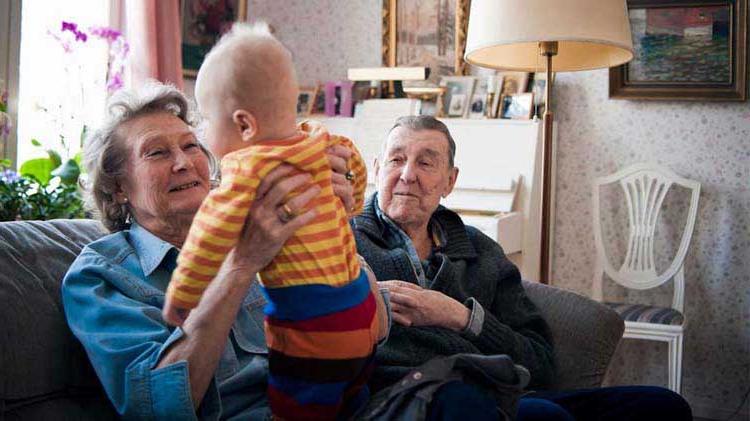 Grandparents with a baby on a couch.